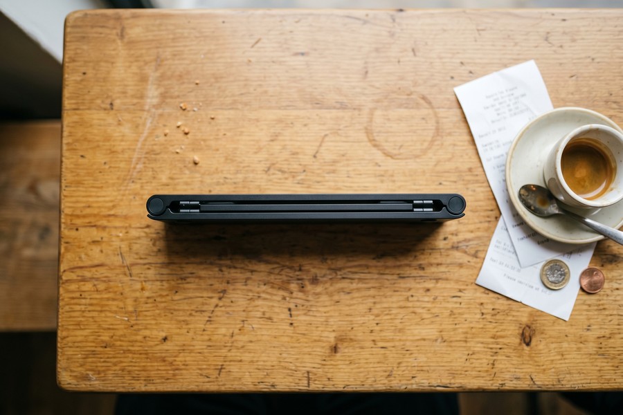 Roost Stand V3 and Nexstand K2 side by side on a coffee shop desk, collapsed and open