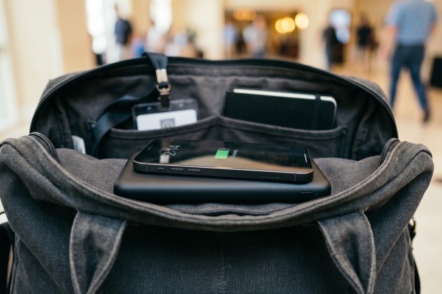 Wireless Qi charging power bank resting on travel bag beside boarding passes and passport