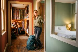 Solo traveler comparing a hostel dorm room and a budget hotel room side by side