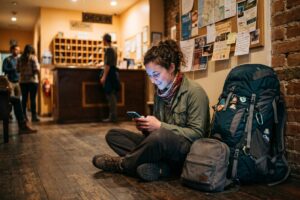 Backpacker searching for last minute accommodation on a smartphone at a busy train station