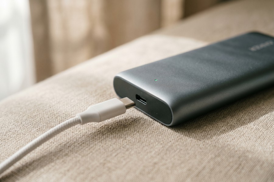 Close-up of a portable charger USB-C port with a cable connected and LED indicator showing charge level