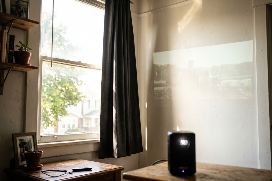 Remote teacher at desk with personal portable projector displaying lesson slides on wall