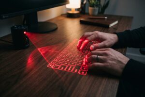 Portable laser keyboard projecting a virtual keyboard onto a flat surface next to a smartphone