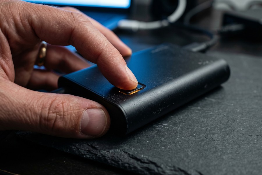 A person pairing a portable laser keyboard with a smartphone on a wooden cafe table