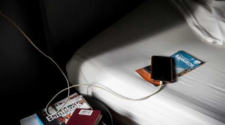 A traveler using a power bank on an airplane with a laptop and phone