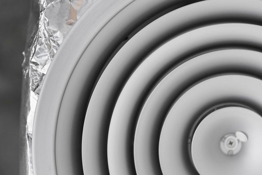 Compact air purifier positioned near a studio apartment bed with visible airflow