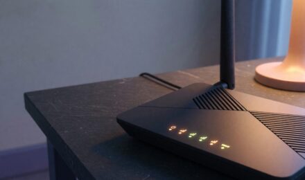 Modern Wi-Fi router on a desk with electricity usage meter display