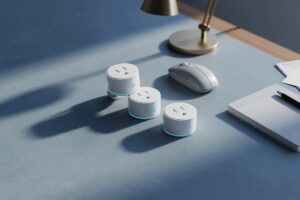 Energy-saving smart plugs plugged into outlet with computer and printer in background