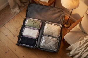 Comparison of packing cubes and compression bags with folded clothing stacked side by side