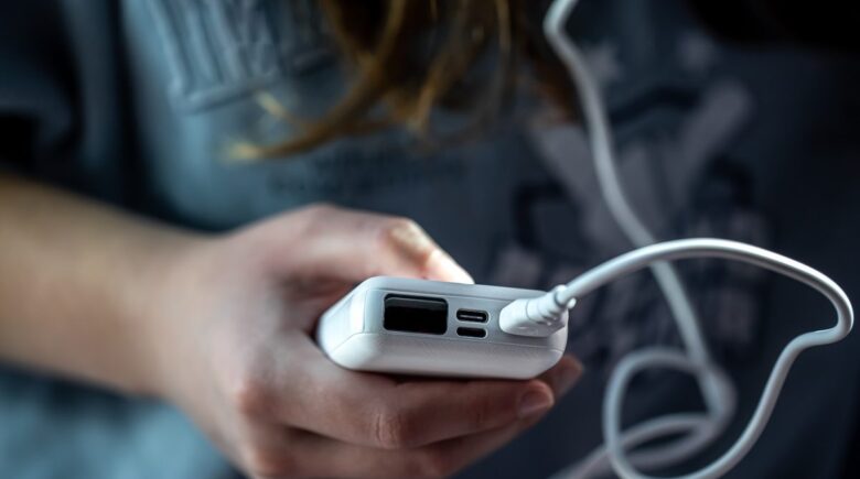 Portable phone charger next to European electrical outlets and luggage