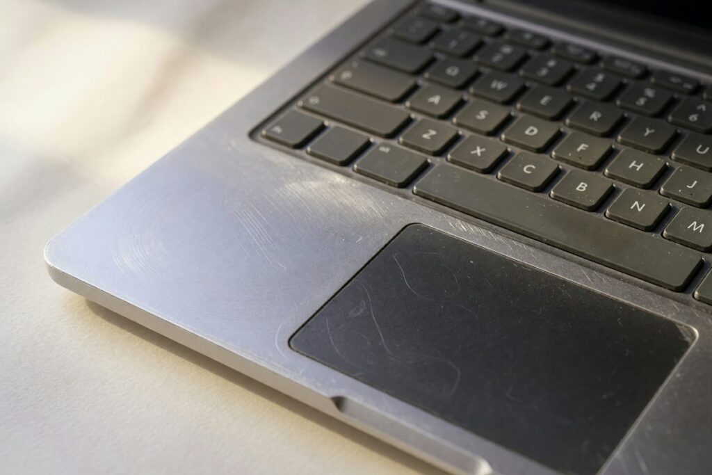 Side-by-side comparison of a refurbished Dell business laptop and a new budget laptop on a desk with carbon footprint symbols