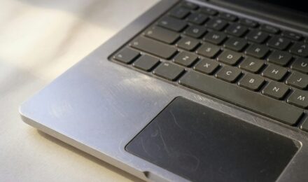 Side-by-side comparison of a refurbished Dell business laptop and a new budget laptop on a desk with carbon footprint symbols