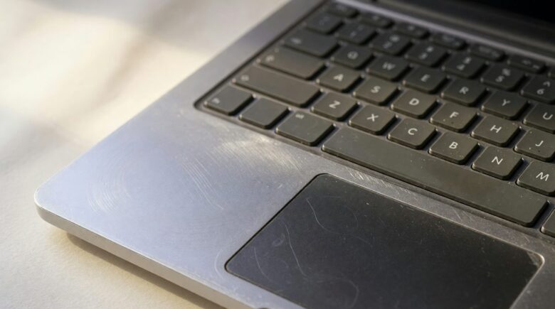 Side-by-side comparison of a refurbished Dell business laptop and a new budget laptop on a desk with carbon footprint symbols