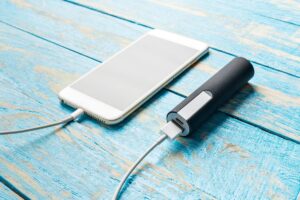 A traveler charging their phone with a portable charger on a plane