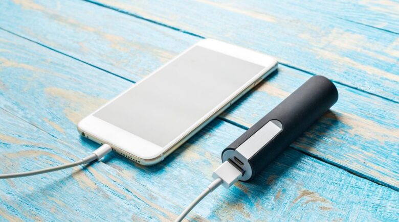 A traveler charging their phone with a portable charger on a plane